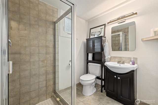 full bath with a stall shower, tile patterned flooring, vanity, and toilet
