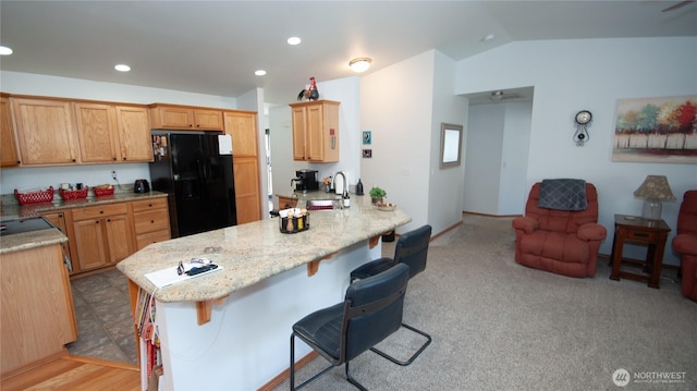 71 E N Bay Pl, Allyn, WA 98524 - kitchen with black fridge with ice dispenser, vaulted ceiling, a kitchen bar, a peninsula, and recessed lighting