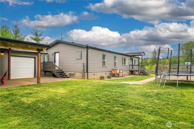 882 Independence Rd, Rochester, WA 98579 - rear view of house with a trampoline, a yard, and an attached garage