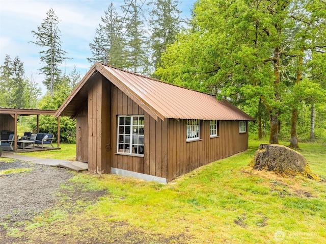view of side of home with metal roof, a yard, and an outbuilding
