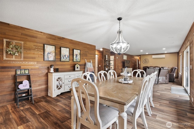 dining space with a wall mounted AC, wood walls, a chandelier, dark wood-style flooring, and recessed lighting
