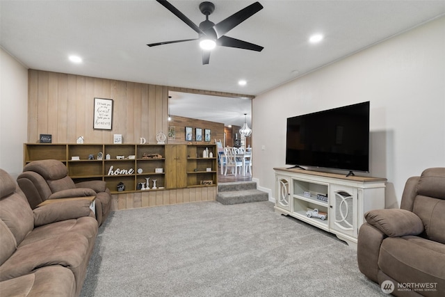 carpeted living room with ceiling fan, wooden walls, and recessed lighting