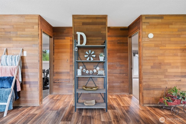 bedroom with wood walls, wood finished floors, and a textured ceiling