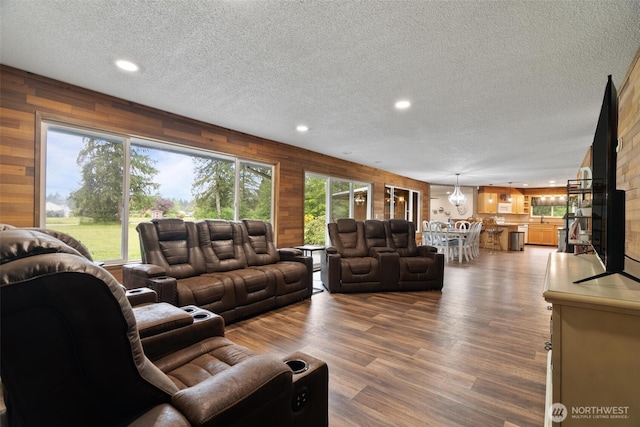 living room featuring a textured ceiling, recessed lighting, wood walls, and wood finished floors