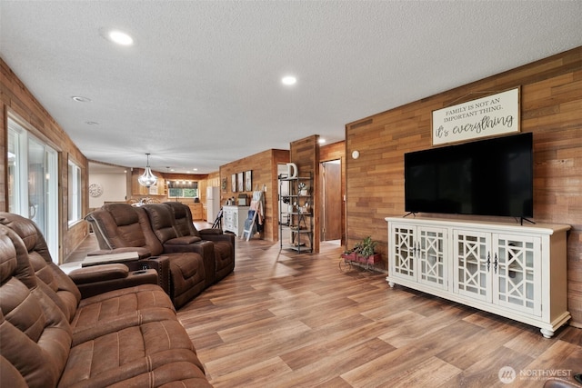 living room with wooden walls, wood finished floors, a textured ceiling, and recessed lighting