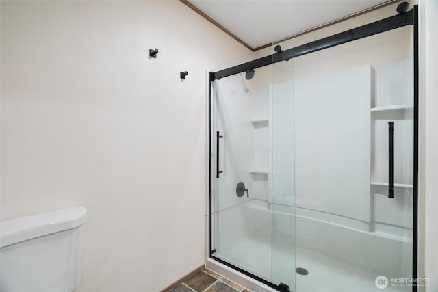 bathroom with a shower stall, toilet, and baseboards