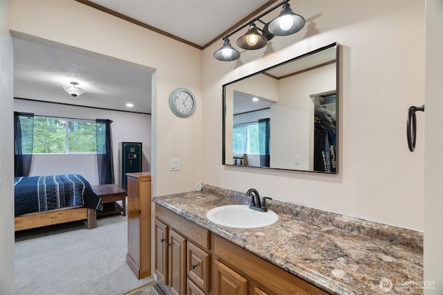 ensuite bathroom featuring crown molding, vanity, and healthy amount of natural light