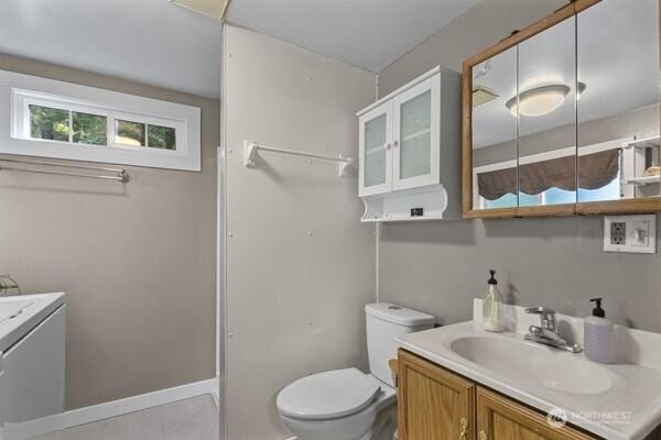 bathroom with vanity, toilet, washer / dryer, and tile patterned flooring