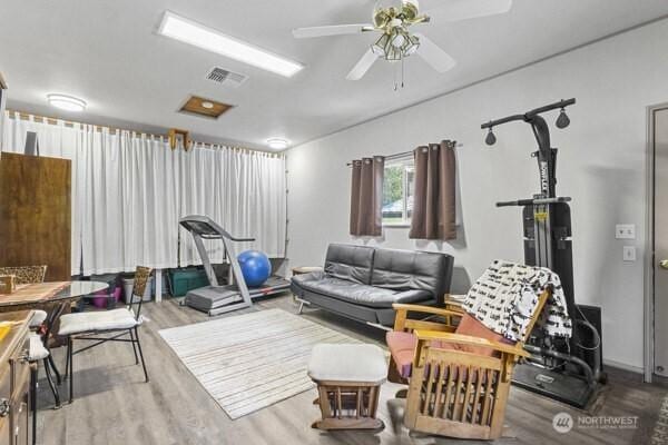 living area with wood finished floors and a ceiling fan
