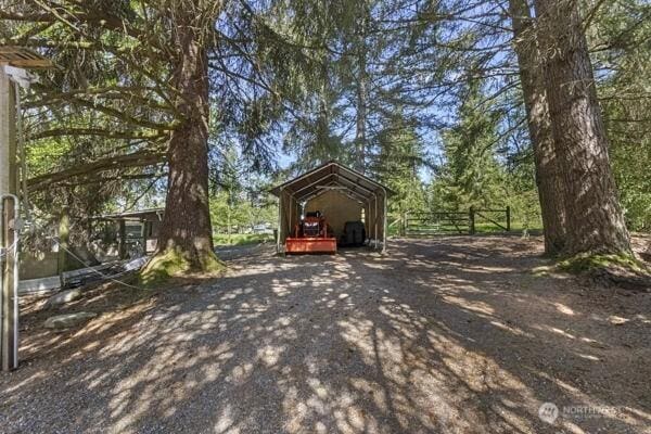 view of outdoor structure with a detached carport and fence