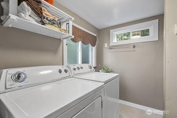 clothes washing area with washing machine and clothes dryer, baseboards, and light tile patterned floors