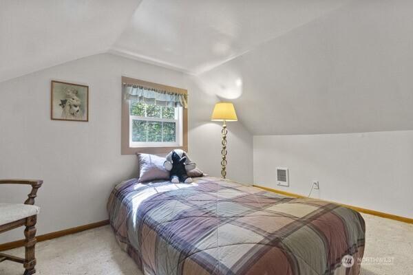 carpeted bedroom featuring lofted ceiling and baseboards