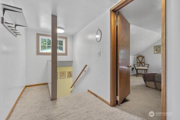 corridor with carpet, vaulted ceiling, an upstairs landing, and baseboards