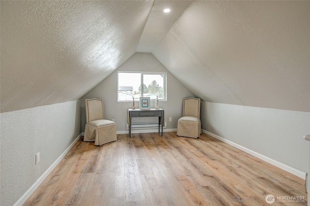 bonus room with wood finished floors, a textured ceiling, vaulted ceiling, and baseboards