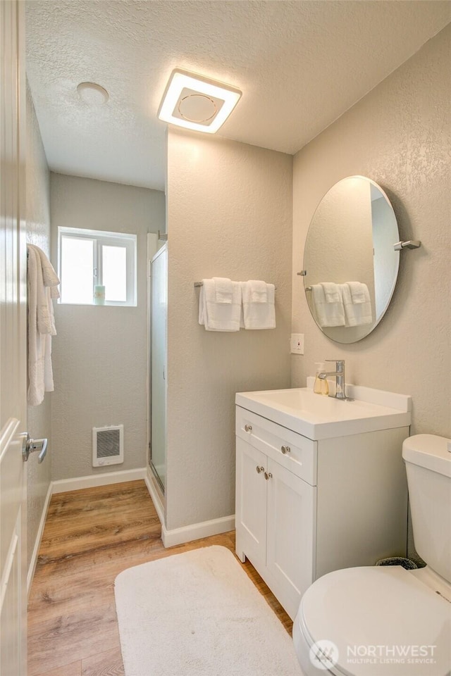 bathroom featuring toilet, a shower stall, a textured ceiling, wood finished floors, and vanity