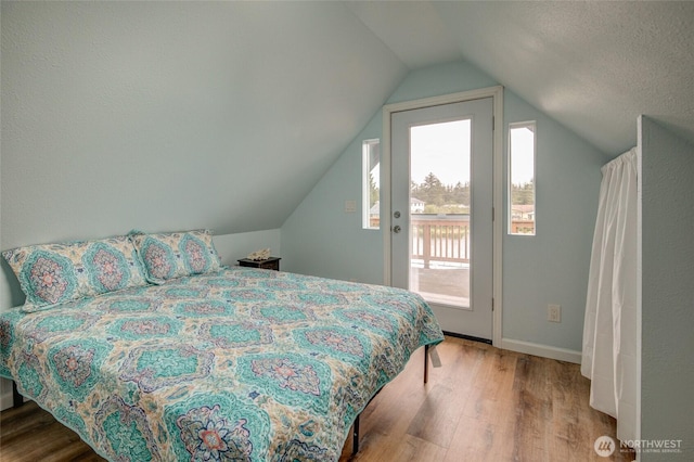 bedroom with access to outside, wood finished floors, lofted ceiling, and baseboards