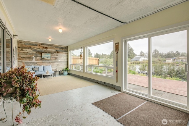 unfurnished sunroom featuring wood walls and carpet floors