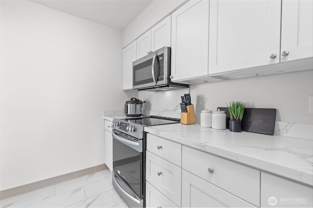 kitchen with stainless steel appliances, light marble finish floors, white cabinetry, light stone counters, and baseboards