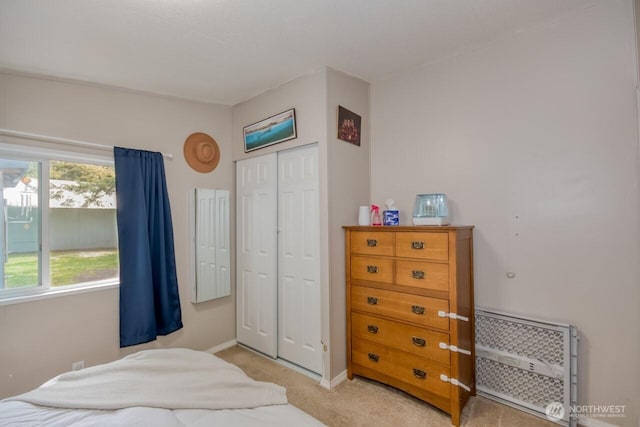 bedroom featuring a closet, light colored carpet, and baseboards