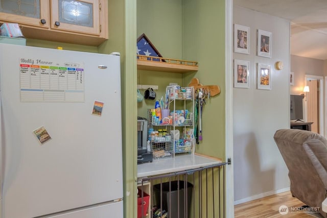 interior space featuring freestanding refrigerator, wood finished floors, and baseboards