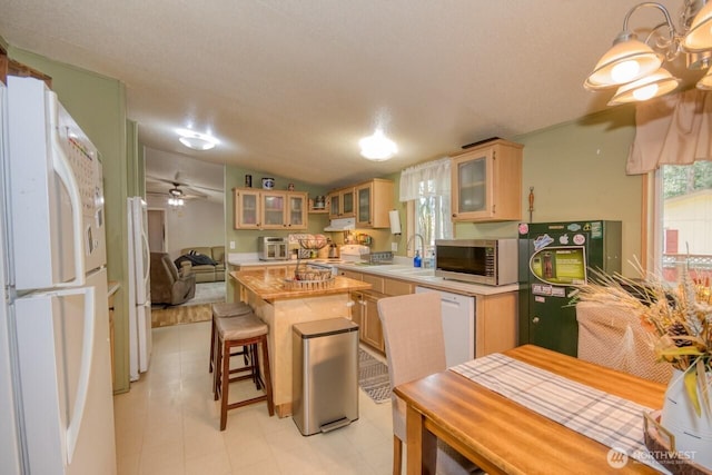 kitchen featuring white appliances, a sink, a kitchen island, glass insert cabinets, and ceiling fan