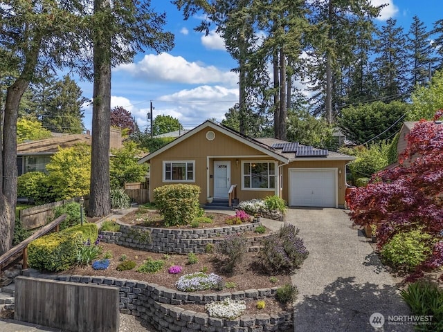 view of front of house featuring an attached garage, driveway, fence, roof mounted solar panels, and a tile roof
