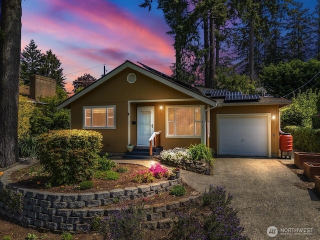 view of front facade with an attached garage, solar panels, driveway, and entry steps