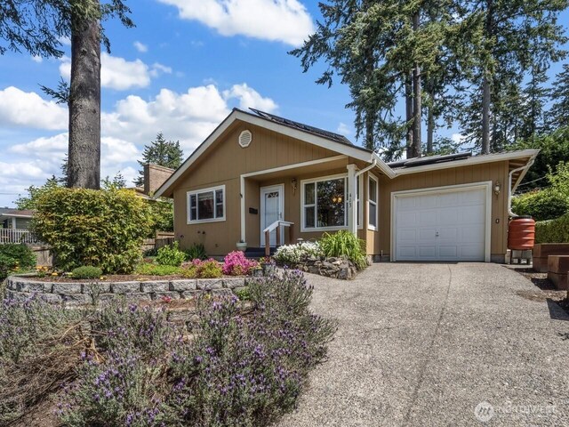 view of front of house with a garage, driveway, and solar panels