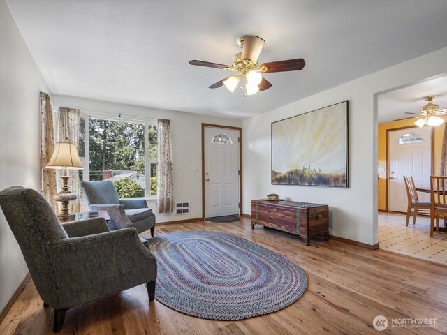 living area featuring a ceiling fan, wood finished floors, and baseboards
