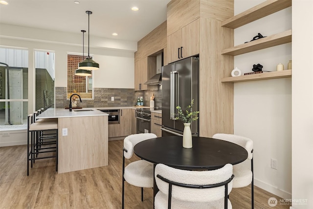 kitchen with light brown cabinetry, appliances with stainless steel finishes, a sink, modern cabinets, and recessed lighting