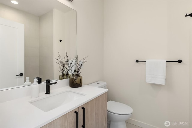 bathroom with toilet, vanity, baseboards, and recessed lighting