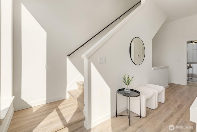 hallway featuring stairway, wood finished floors, and baseboards