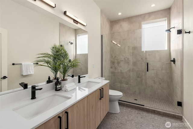 bathroom featuring a stall shower, plenty of natural light, double vanity, toilet, and recessed lighting