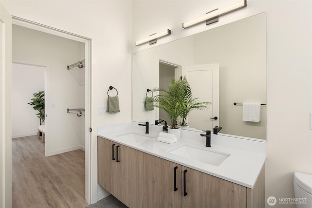 full bath with wood finished floors, double vanity, toilet, and baseboards