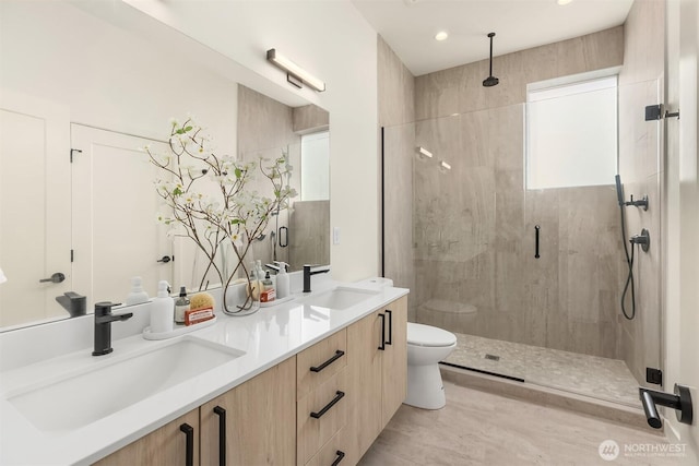 bathroom featuring a shower stall, toilet, double vanity, and recessed lighting