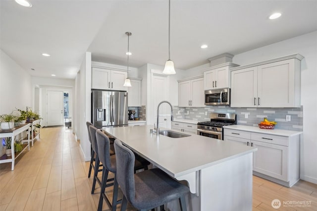 18009 NE 46th Ct, Vancouver, WA 98686 - kitchen with stainless steel appliances, a sink, an island with sink, a breakfast bar area, and tasteful backsplash