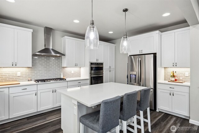 9844 Prospect Pl, Gig Harbor, WA 98332 - kitchen with wall chimney range hood, appliances with stainless steel finishes, decorative backsplash, dark wood finished floors, and light countertops