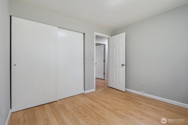 unfurnished bedroom featuring light wood-style flooring, a closet, and baseboards