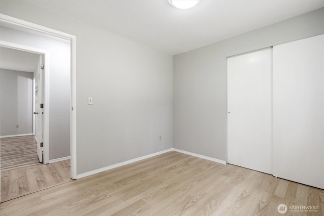 unfurnished bedroom featuring wood finished floors, a closet, and baseboards
