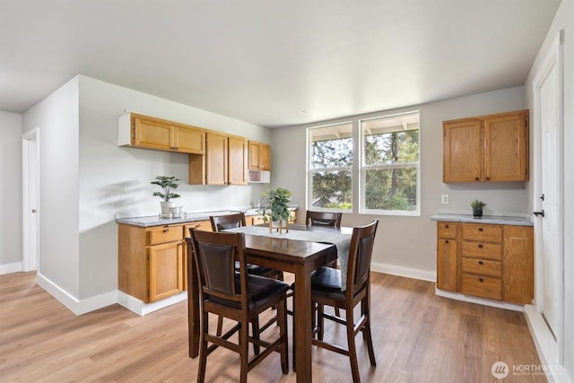 dining area featuring light wood-style flooring and baseboards
