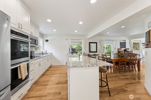 kitchen featuring appliances with stainless steel finishes, a sink, a kitchen breakfast bar, recessed lighting, and light wood-style flooring