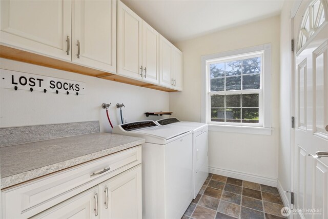 clothes washing area featuring cabinet space, washing machine and dryer, baseboards, and stone finish flooring