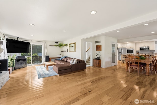 living area featuring stairs, light wood-type flooring, and recessed lighting