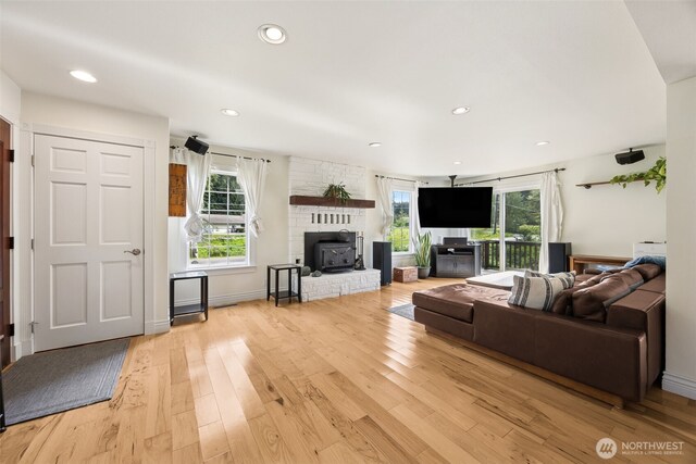 living area with healthy amount of natural light, light wood-type flooring, recessed lighting, and a wood stove