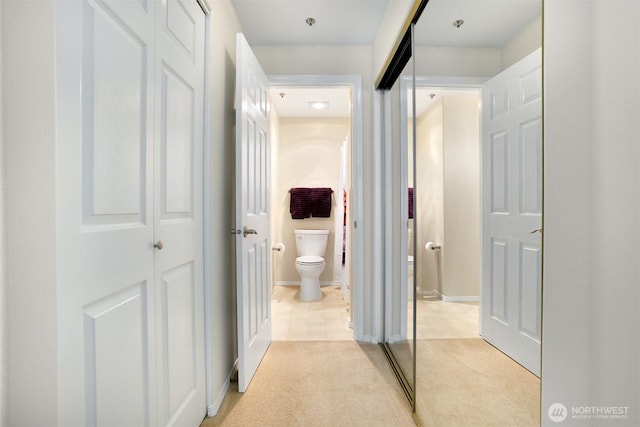 hallway featuring light carpet and baseboards