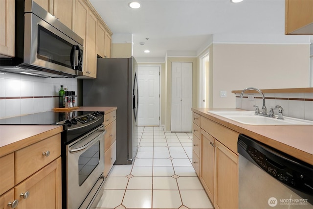 kitchen with stainless steel appliances, a sink, light brown cabinets, decorative backsplash, and recessed lighting