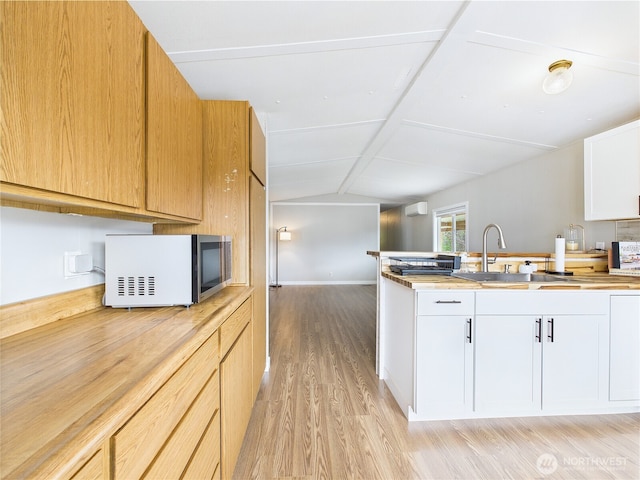 212 Old Owen Rd Unit 43, Sultan, WA 98294 - kitchen featuring light wood-style floors, lofted ceiling, white cabinetry, a sink, and a peninsula