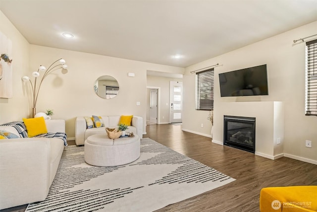 living room with wood finished floors, baseboards, a glass covered fireplace, and recessed lighting