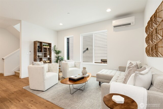 living area featuring an AC wall unit, wood finished floors, stairs, baseboards, and recessed lighting