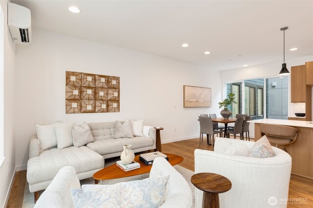 living area featuring a wall mounted air conditioner, recessed lighting, light wood-type flooring, and baseboards